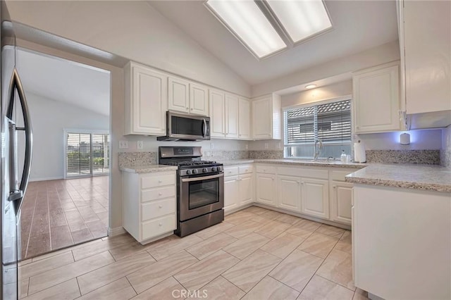 kitchen featuring white cabinets, stainless steel appliances, lofted ceiling, and sink