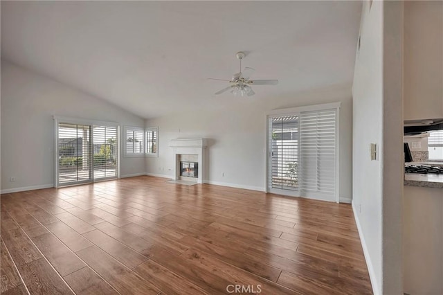 unfurnished living room featuring hardwood / wood-style floors, lofted ceiling, ceiling fan, and a healthy amount of sunlight