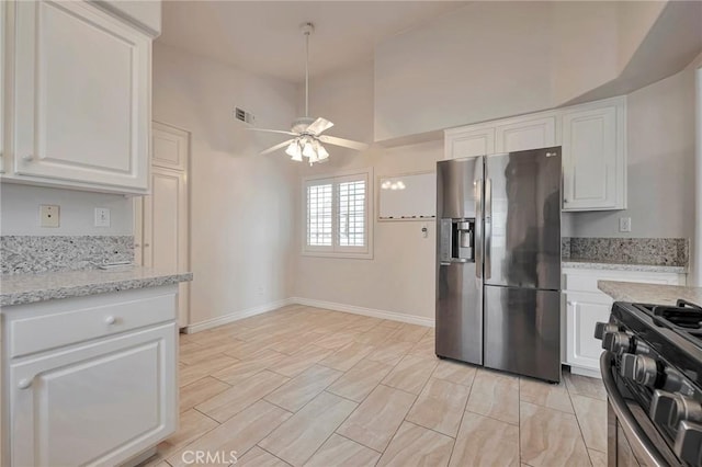 kitchen with light stone countertops, stainless steel refrigerator with ice dispenser, ceiling fan, black range, and white cabinets