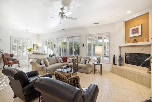 tiled living room with a tiled fireplace and ceiling fan