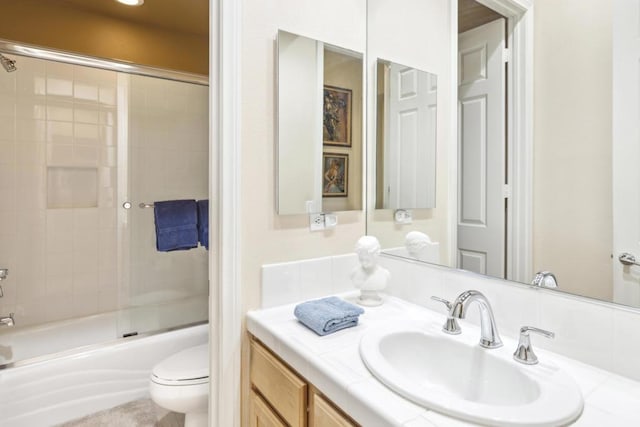 full bathroom featuring vanity, toilet, and bath / shower combo with glass door