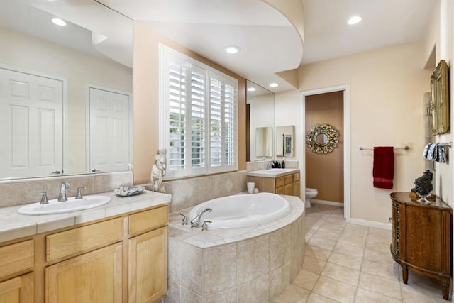 bathroom with tile patterned floors, vanity, toilet, and tiled bath