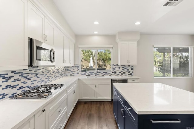 kitchen featuring sink, dark hardwood / wood-style floors, decorative backsplash, white cabinets, and appliances with stainless steel finishes