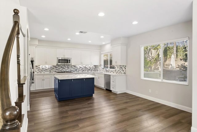 kitchen with dark hardwood / wood-style flooring, tasteful backsplash, stainless steel appliances, a center island, and white cabinetry