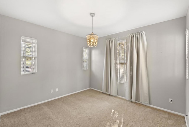 empty room featuring a notable chandelier and carpet floors