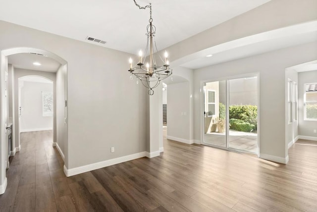 unfurnished dining area with dark wood-type flooring and an inviting chandelier