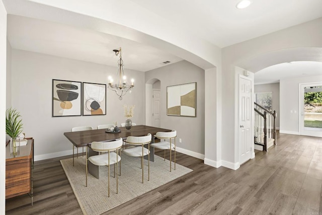 dining room with dark wood-type flooring and an inviting chandelier