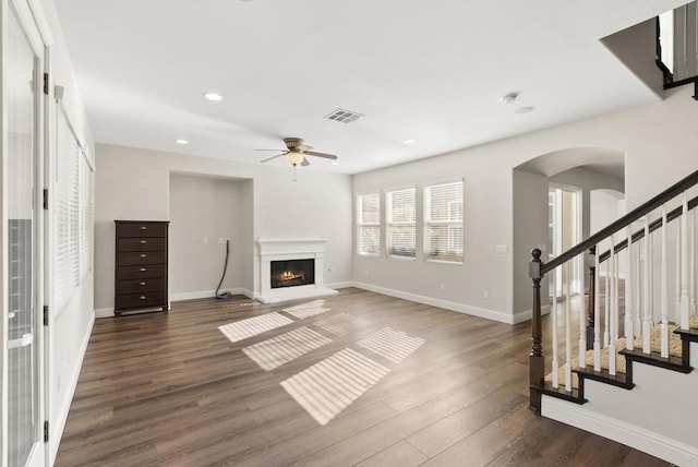 unfurnished living room featuring ceiling fan and dark wood-type flooring