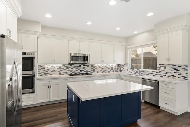 kitchen with dark wood-type flooring, white cabinets, stainless steel appliances, and a kitchen island