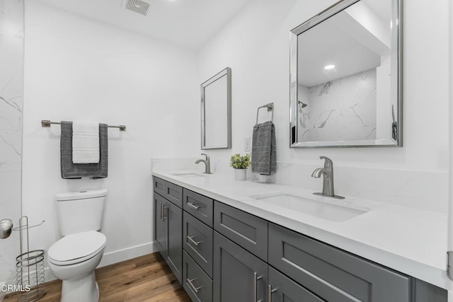 bathroom featuring hardwood / wood-style flooring, vanity, toilet, and a tile shower