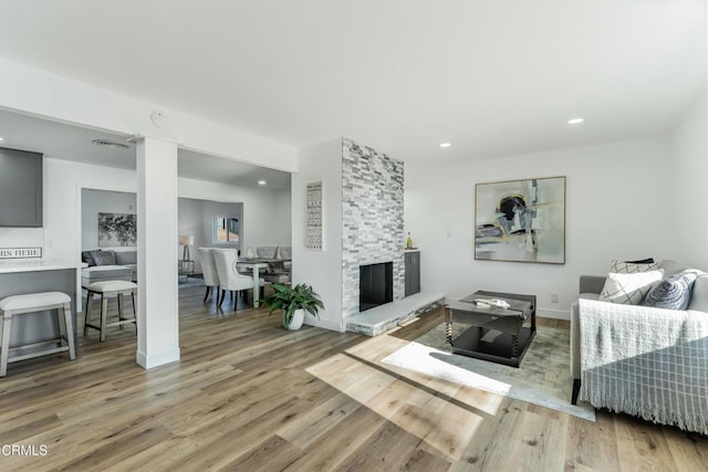 living room featuring a stone fireplace and light wood-type flooring