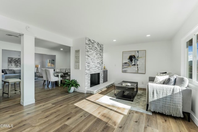 living room with hardwood / wood-style floors and a stone fireplace