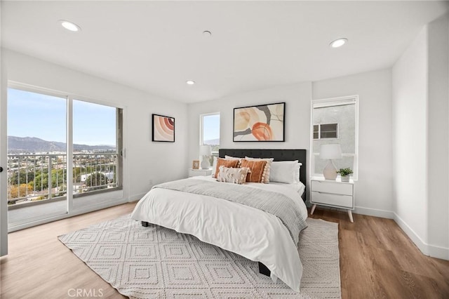 bedroom with access to outside, a mountain view, and light hardwood / wood-style flooring