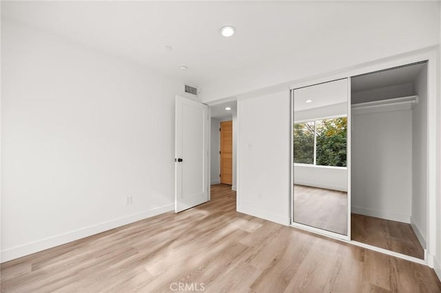 unfurnished bedroom with a closet and light hardwood / wood-style flooring