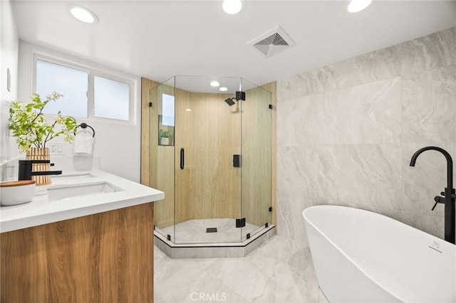 bathroom with vanity, shower with separate bathtub, and tile walls