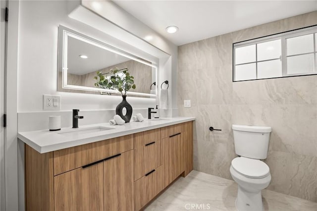 bathroom with vanity, tile walls, and toilet