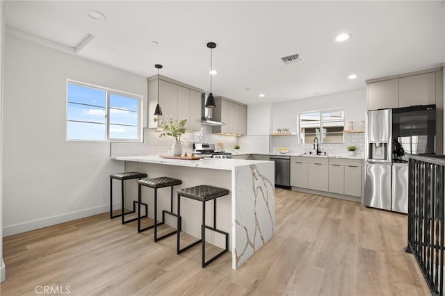 kitchen with pendant lighting, light wood-type flooring, stainless steel appliances, and plenty of natural light