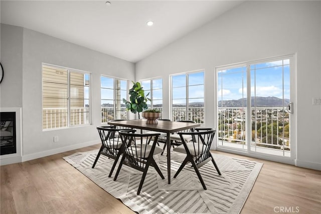 dining space with light wood-type flooring, high vaulted ceiling, and plenty of natural light