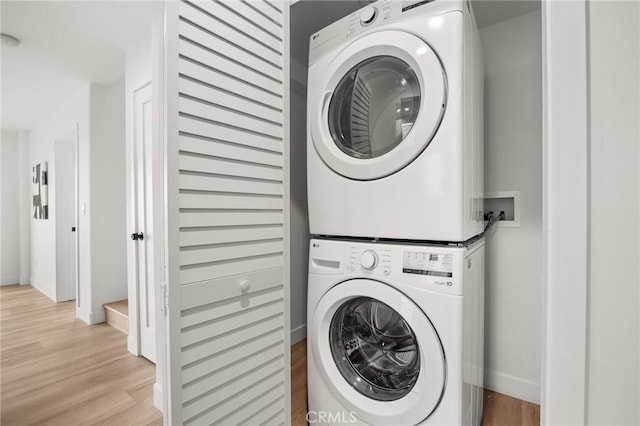 clothes washing area featuring light hardwood / wood-style flooring and stacked washer / drying machine