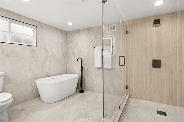 bathroom with separate shower and tub, toilet, and tile walls