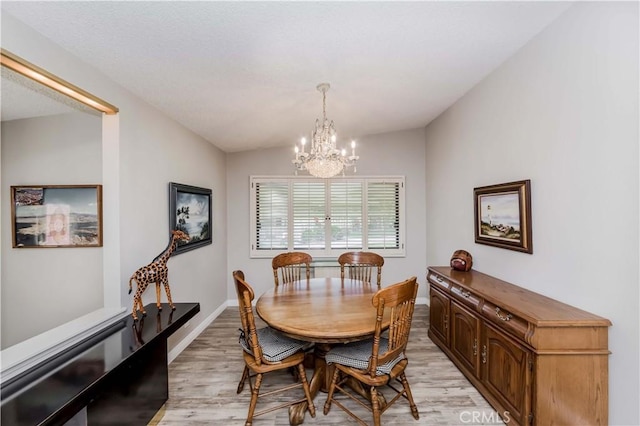 dining area with a chandelier, light hardwood / wood-style floors, and vaulted ceiling