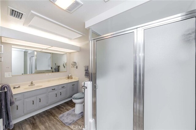 bathroom with vanity, hardwood / wood-style flooring, toilet, and a shower with shower door