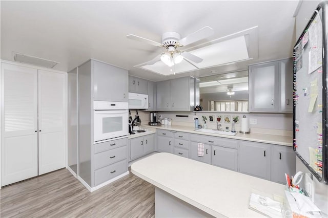 kitchen featuring ceiling fan, sink, light hardwood / wood-style floors, white appliances, and gray cabinets