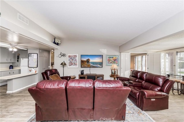 living room with ceiling fan, light hardwood / wood-style floors, and lofted ceiling