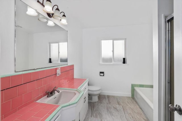 bathroom featuring toilet, a tub to relax in, tasteful backsplash, and vanity