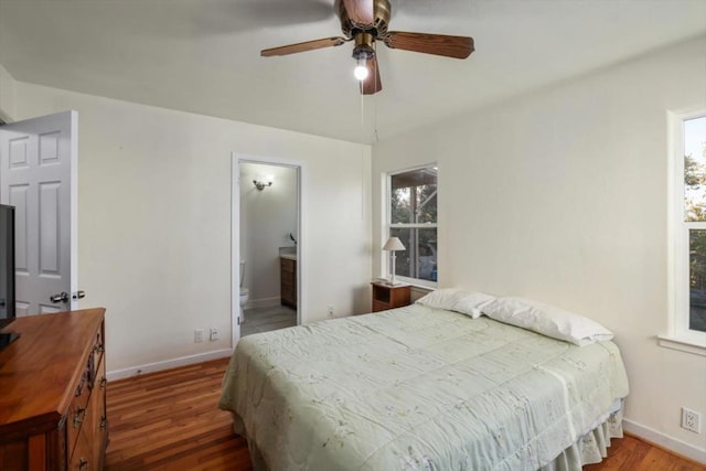 bedroom featuring ensuite bathroom, hardwood / wood-style floors, ceiling fan, and multiple windows