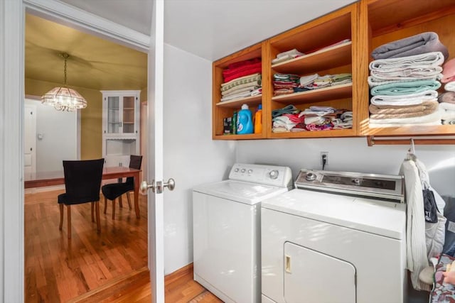 laundry area with washer and clothes dryer, an inviting chandelier, and light wood-type flooring