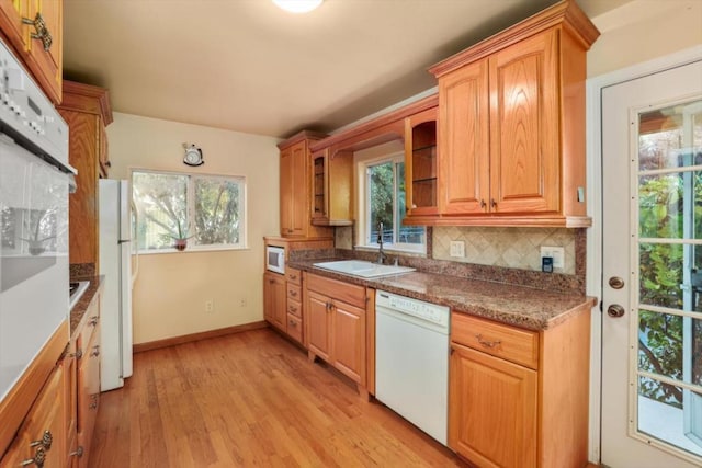 kitchen with white appliances, light hardwood / wood-style flooring, decorative backsplash, and sink