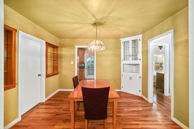 dining area with ceiling fan with notable chandelier and hardwood / wood-style flooring