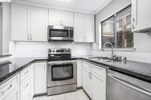 kitchen featuring white cabinets, stainless steel appliances, dark stone countertops, sink, and light tile patterned flooring