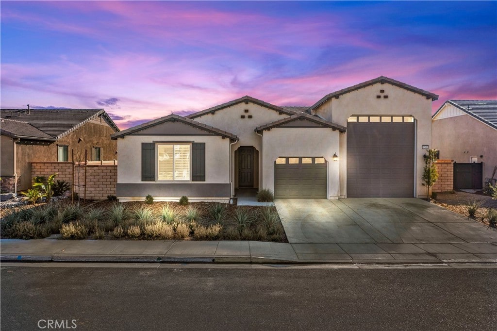 mediterranean / spanish-style house featuring a garage, driveway, fence, and stucco siding