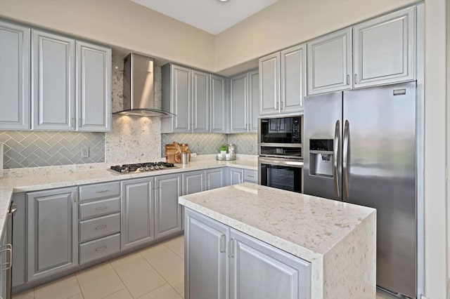 kitchen featuring decorative backsplash, gray cabinets, wall chimney exhaust hood, and appliances with stainless steel finishes