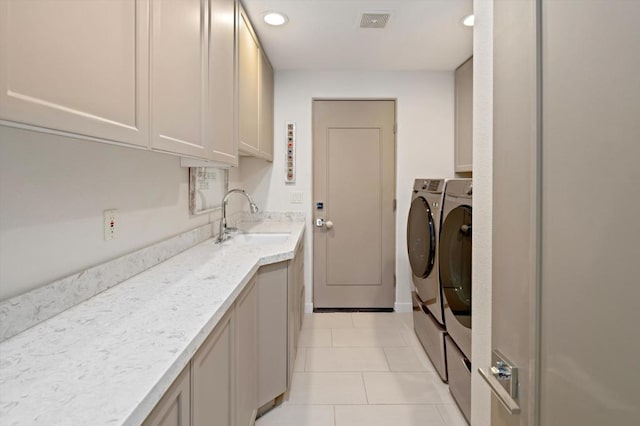 laundry area featuring cabinets, light tile patterned flooring, sink, and washing machine and clothes dryer