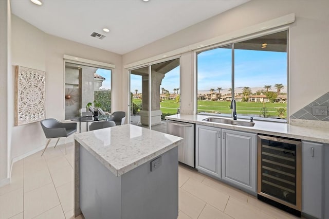 kitchen featuring sink, gray cabinets, beverage cooler, and a center island