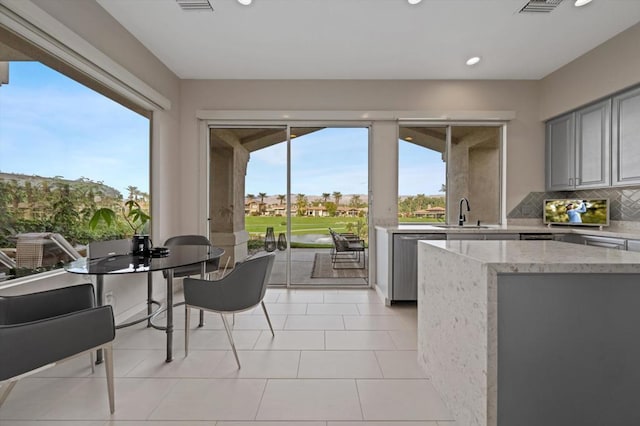 kitchen featuring sink, gray cabinetry, tasteful backsplash, light tile patterned floors, and dishwasher