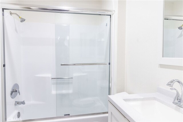 bathroom featuring combined bath / shower with glass door and vanity