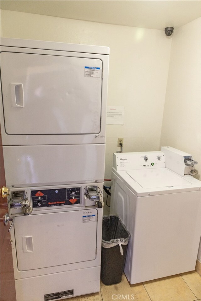 clothes washing area featuring stacked washing maching and dryer and light tile patterned floors