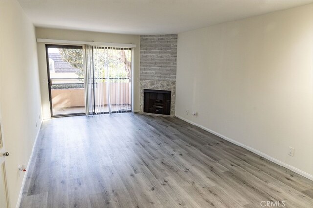 unfurnished living room featuring a large fireplace and light hardwood / wood-style flooring