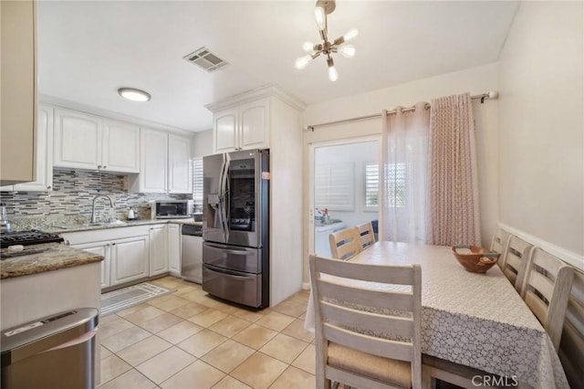 kitchen featuring white cabinets, light stone counters, appliances with stainless steel finishes, and a chandelier