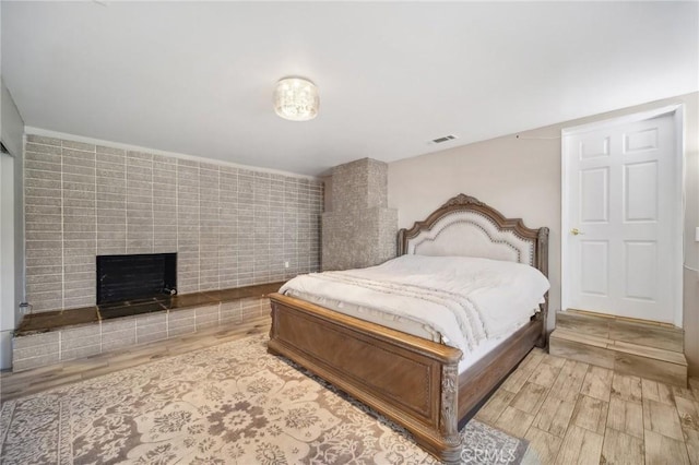 bedroom featuring light wood-type flooring and a fireplace