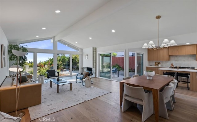 dining area with lofted ceiling with beams, a notable chandelier, plenty of natural light, and light wood finished floors