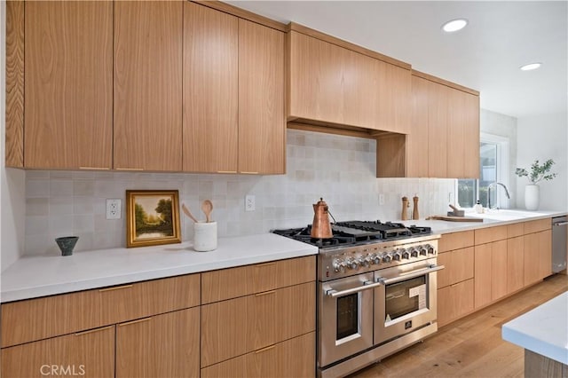 kitchen featuring light wood-style flooring, light brown cabinets, backsplash, appliances with stainless steel finishes, and light countertops