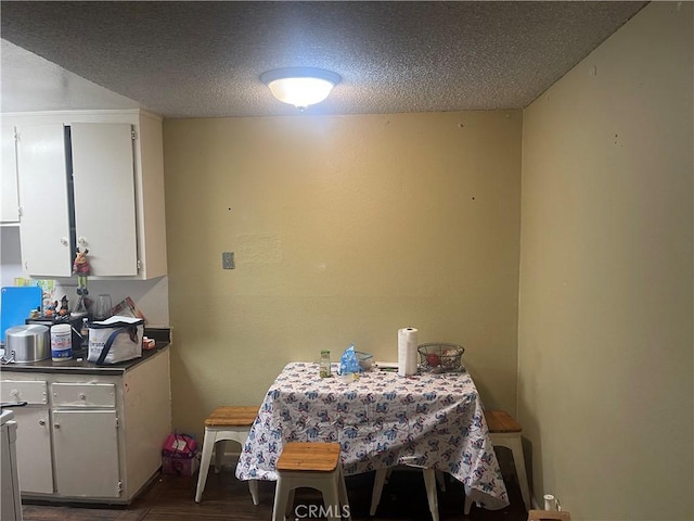 dining area featuring dark wood-type flooring and a textured ceiling