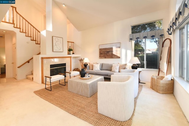 carpeted living room featuring a tiled fireplace and a towering ceiling