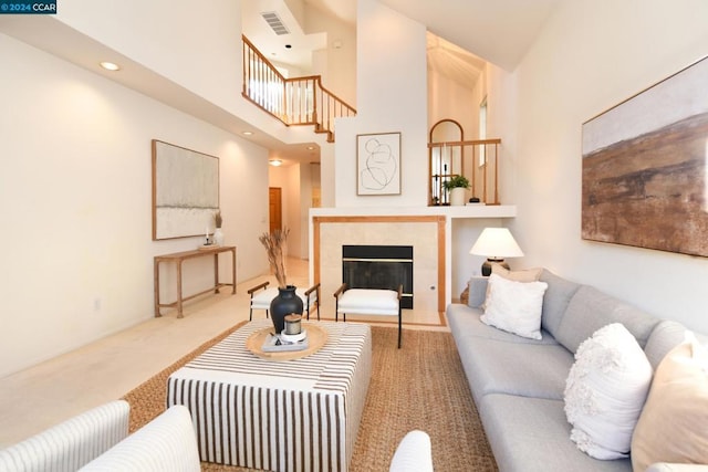 living room with a towering ceiling and a tiled fireplace