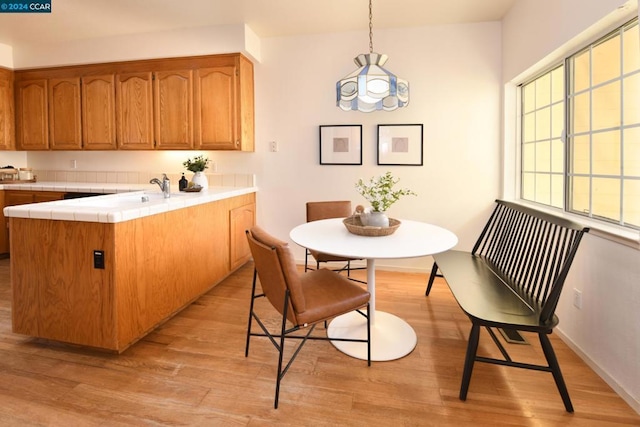 kitchen featuring hanging light fixtures, kitchen peninsula, and light hardwood / wood-style flooring